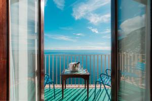 a balcony with a table and chairs and the ocean at Villa Nettuno in Positano