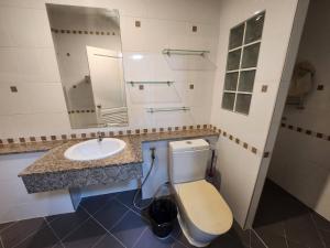 een badkamer met een wastafel, een toilet en een spiegel bij Phanason Private Home soi 4 in Kathu