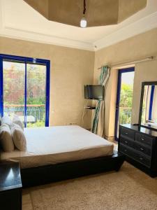 um quarto com uma cama com uma cómoda e 2 janelas em Villa Traditional Family em Marrakech