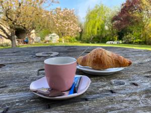 una taza de café y una pastelería en una mesa de madera en Les Lavandières, en Saint-Hilaire-la-Palud