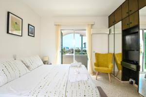 a bedroom with a large white bed and a yellow chair at Villa 361 - Family Great Escape to Fig Tree Bay area in Protaras
