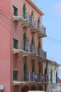 a pink building with blue balconies on the side of it at Axiothea Hotel in Paphos
