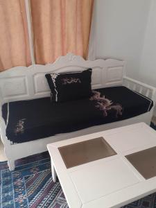 a bed with a black and white bed frame and a table at Appartement parfait pour les couples, bien équipé, à Hammamet centre 200m de la plage in Hammamet
