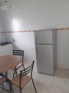 eine Küche mit einem Tisch und einem weißen Kühlschrank in der Unterkunft Appartement parfait pour les couples, bien équipé, à Hammamet centre 200m de la plage in Hammamet