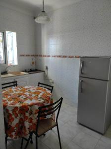 una cucina con tavolo e frigorifero di Appartement parfait pour les couples, bien équipé, à Hammamet centre 200m de la plage a Hammamet