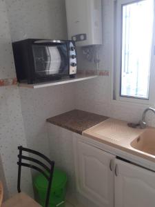 a small kitchen with a microwave and a sink at Appartement parfait pour les couples, bien équipé, à Hammamet centre 200m de la plage in Hammamet