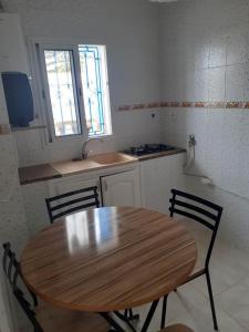 a kitchen with a wooden table and two chairs at Appartement parfait pour les couples, bien équipé, à Hammamet centre 200m de la plage in Hammamet