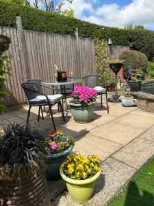 une terrasse avec une table, des chaises et des plantes en pot dans l'établissement Acorn Cottage, à Ollerton