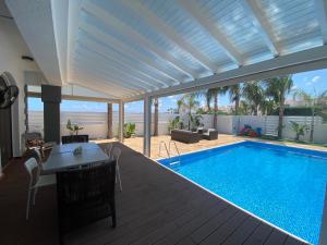 a house with a swimming pool and a patio with a table at Villa Angel - Exotic Villa 200m From Beach in Paralimni