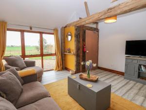 a living room with a couch and a tv at Bee Happy Barn in Norwich