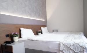 イスタンブールにあるニコンヤ ポート スイート＆ホテルのベッドルーム(花の飾られた白い大型ベッド付)