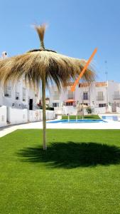 a large straw umbrella in a field of grass at Casa-Mar Nerja in Nerja