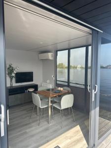 a dining room with a table and chairs and a large window at Stoere HOUSEBOAT op toplocatie! in Belt-Schutsloot