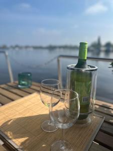 Una botella de vino y dos copas en una mesa. en Stoere HOUSEBOAT op toplocatie!, en Belt-Schutsloot