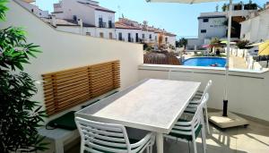 a white table and chairs on a balcony with a pool at Casa-Mar Nerja in Nerja