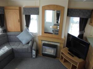 a living room with a couch and a tv and a fireplace at Golden Sands: Mirage IIII:- 6 Berth, Access to the beach in Ingoldmells