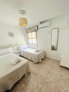 two beds in a room with white walls and tile floors at Apartamento El Arenal - Free Parking in Córdoba