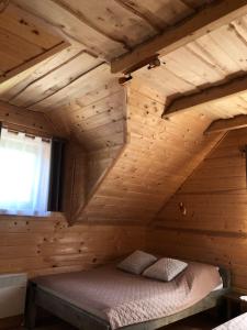 pokój z łóżkiem w drewnianym domku w obiekcie Wiejski Zakątek nad Wigrami w mieście Rosochaty Róg