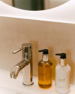 two bottles of soap sitting on a bathroom sink at Eterrano Seaside Retreat in Parga