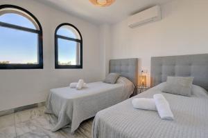 twee bedden in een witte kamer met twee ramen bij 4 Bedroom Townhouse 200 meters from the Beach! in Estepona