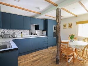 a kitchen with blue cabinets and a table with chairs at Cattle Tree Cottage in Cardigan
