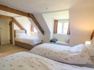 two beds in a room with two windows at Cattle Tree Cottage in Cardigan