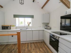uma cozinha com armários brancos, um lavatório e uma janela em The Parlour em Cardigan
