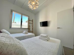 a white bedroom with two beds and a tv at Sun golf house in Maspalomas