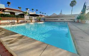 a large blue swimming pool in a building with palm trees at Sun golf house in Maspalomas