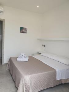 Habitación blanca con cama y toallas. en SeA Beach Home, en Torre Lapillo