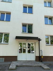 een wit gebouw met een deur ervoor bij Valdemāra apartamenti in Valmiera