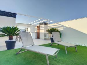 2 chaises blanches assises sur une terrasse avec pelouse dans l'établissement Levansur Apartment - 9109, à San Pedro del Pinatar