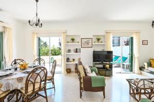 a living room with a table and chairs and a television at Villa 361-Walk to Protaras Fig Tree Bay & Amenities in Protaras