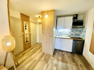 a kitchen with white cabinets and a wooden floor at Bel appartement en bord de mer avec piscine in Lacanau-Océan