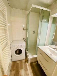 a bathroom with a washing machine and a shower at Bel appartement en bord de mer avec piscine in Lacanau-Océan