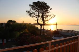 een zonsondergang boven het water met een boom en een hek bij Nikos Seaside Apartments in (( Litherés ))