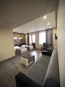 sala de estar con 2 camas y sofá en Bien hotel en Ereván