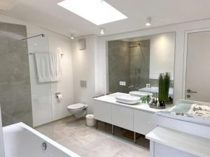 biała łazienka z wanną, toaletą i umywalką w obiekcie Bodensee Loft in Strandnähe w mieście Lochau