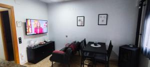 a dining room with a table and chairs and a television at Apartamento entero con terraza en el centro de Rubí in Rubí