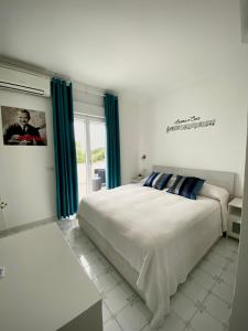 una camera bianca con un grande letto con tende blu di Capri Melody ad Anacapri