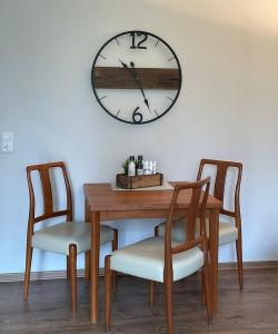 una mesa con dos sillas y un reloj en la pared en Ferienwohnung Lynn, en Büsum
