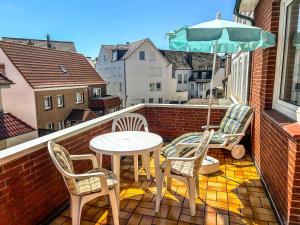 einen Balkon mit einem Tisch, Stühlen und einem Sonnenschirm in der Unterkunft Haus Tida in Norderney