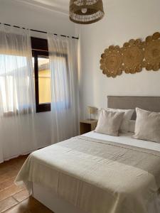 a bedroom with a large white bed and a window at Habitaciones Carmencita in Bolonia