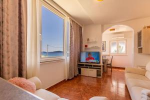 a living room with a couch and a tv and a window at Lanterna Puntamika apt. near beach in Zadar