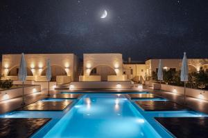 una piscina por la noche con la luna en el cielo en Zaitun Luxury Suites en Karterados