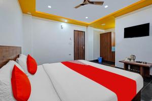 - une chambre avec un grand lit et des oreillers rouges dans l'établissement OYO Flagship Vasudha inn, Hoskote, à Bangalore