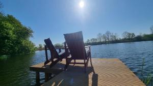 ein Paar Stühle auf einem Steg auf einem See in der Unterkunft Gutshof Kämmerich in Altkalen