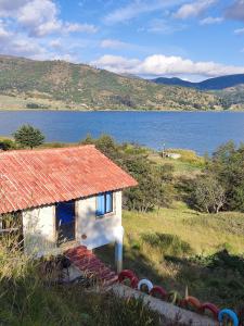 ein kleines Haus mit einem orangenen Dach neben einem Wasserkörper in der Unterkunft Cabañas Villas Del Lago in Cuítiva