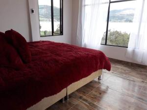Schlafzimmer mit einem großen roten Bett und Fenstern in der Unterkunft Cabañas Villas Del Lago in Cuítiva