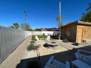 a backyard with white chairs and a table and a fence at Aloha Apartman in Rakamaz +30 photos